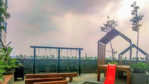 A playground with swings, a slide, and benches. - Neat Studio At Lrt City Bekasi Apartment (Bekasi)