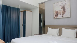 A hotel room with a large bed, a mirror, a painting of a deer, and a wardrobe. - Neat Studio At Lrt City Bekasi Apartment (Bekasi)