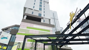 A multi-story building with a modern architectural design, featuring a mix of glass and concrete facades. - Simple Studio At Lrt City Bekasi Apartment By Travelio (Bekasi)