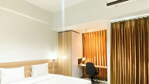 A hotel room with a large bed, a desk, and a chair. - Simple Studio At Lrt City Bekasi Apartment By Travelio (Bekasi)