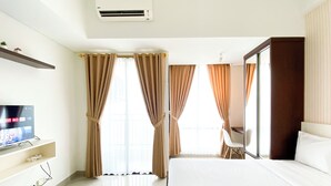 A hotel room with a bed, a TV, a desk, and a chair. - Homey And Nice Studio At Lrt City Bekasi Apartment (Bekasi)