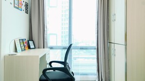 A modern office space with a desk, chair, and a large window with curtains. - Cozy Stay Studio At Lrt City Bekasi Apartment (Bekasi)