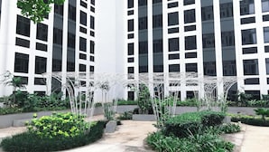 Un bâtiment moderne à la façade blanche et aux nombreuses fenêtres. On aperçoit, au premier plan, des plantes vertes et une structure métallique blanche.