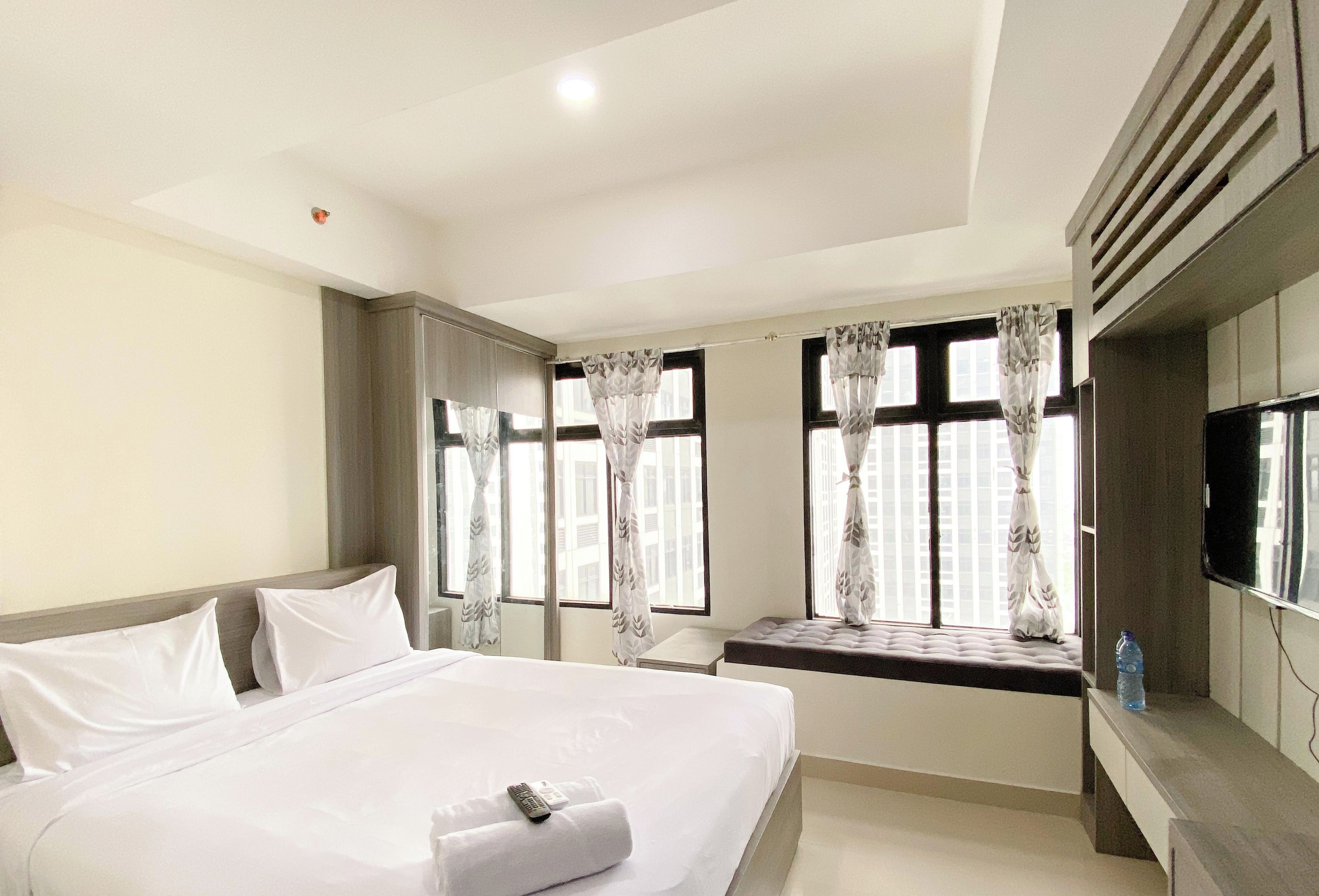 Une chambre d’hôtel avec un grand lit, un téléviseur fixé au mur et une fenêtre avec des rideaux.