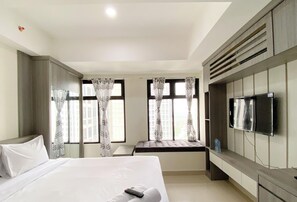 Una habitación de hotel con una cama grande, un televisor montado en la pared y una ventana con cortinas.