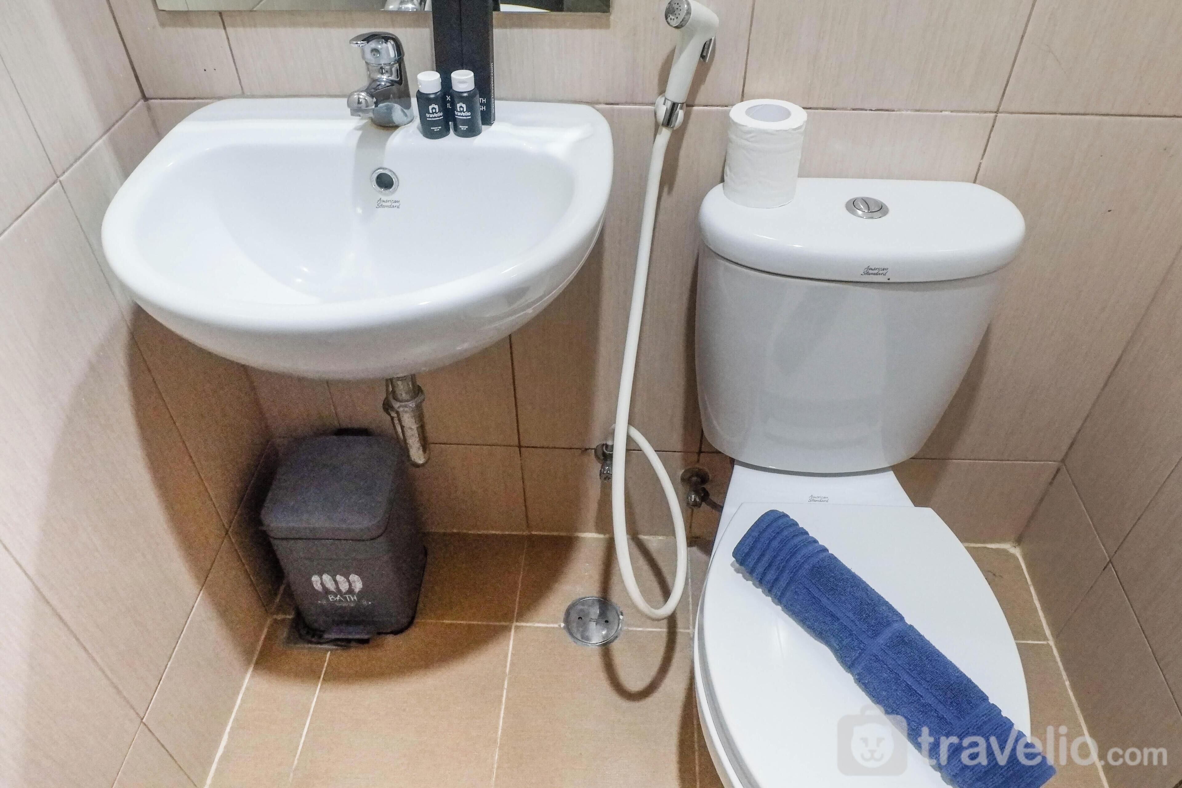A bathroom with a white sink, toilet, and a towel on the toilet seat.