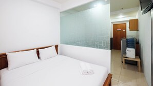 A hotel room with a bed, a water dispenser, and a television mounted on the wall. - Simply Studio Room At Titanium Square Apartment (Jakarta)