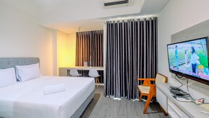 Ein Hotelzimmer mit Bett, Schreibtisch, Stuhl, Fernseher und Vorhängen.