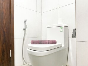A modern bathroom with a white toilet, a shower, and a toilet paper holder.