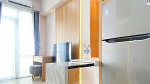 A modern kitchen with a marble countertop, a built-in dishwasher, a stainless steel refrigerator, and wooden cabinets. - Wonderful And Homey Studio Vasanta Innopark Apartment (Cikarang)
