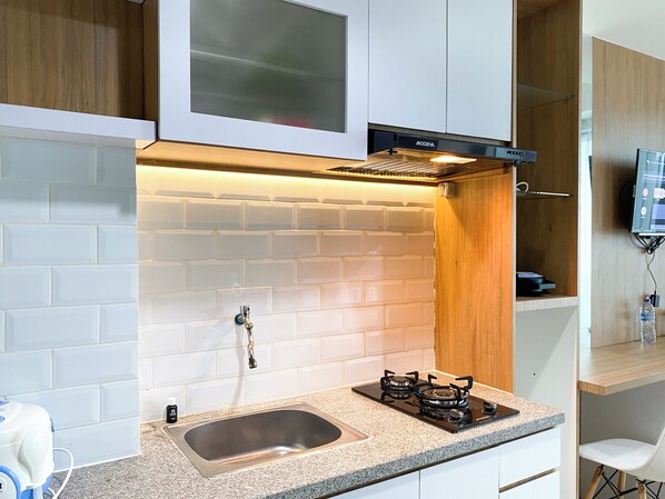 A modern kitchen with white subway tiles, a stainless steel sink, a gas stove, and wooden cabinets.