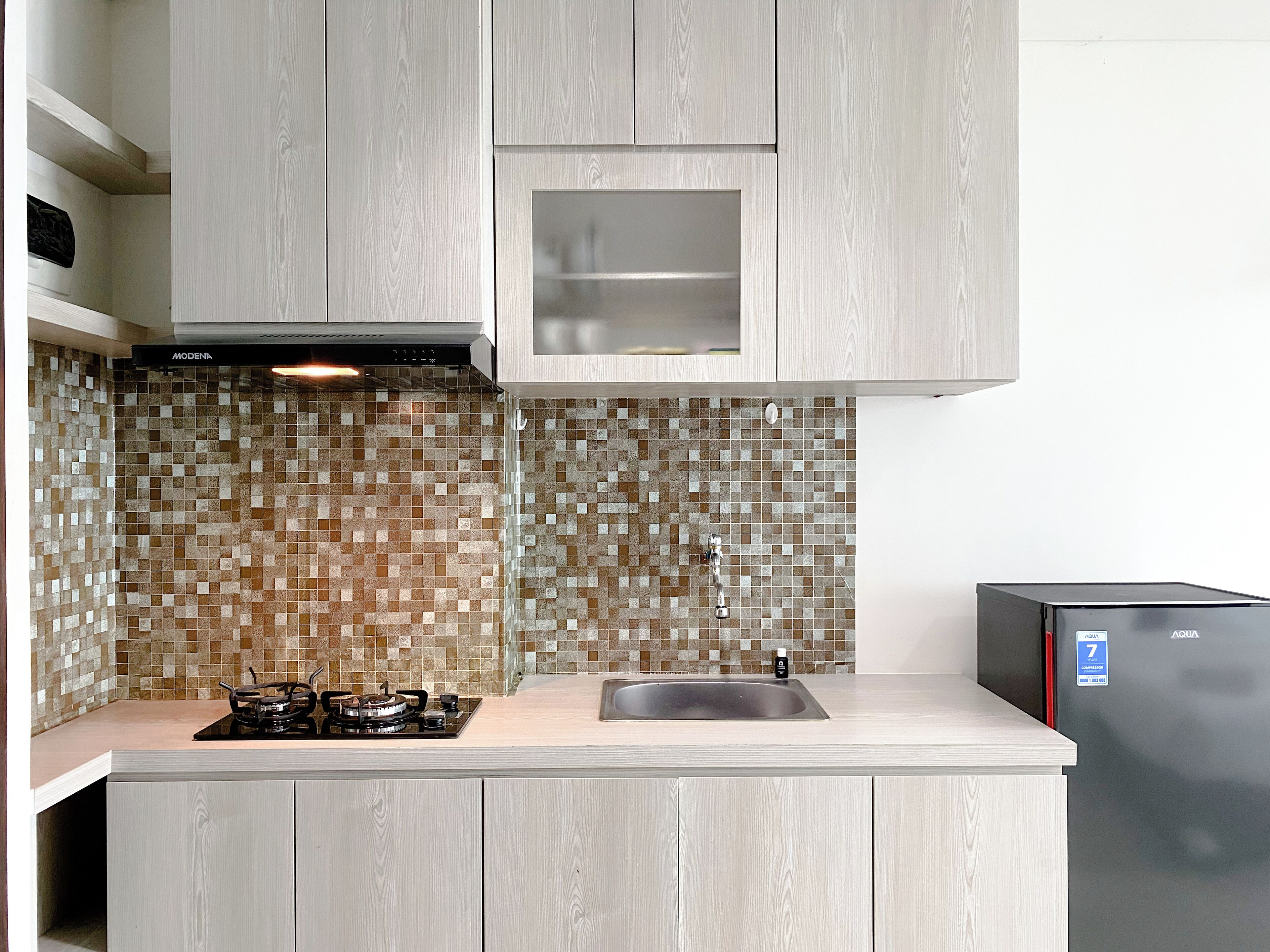 A kitchen with a gas stove, a sink, and a refrigerator.