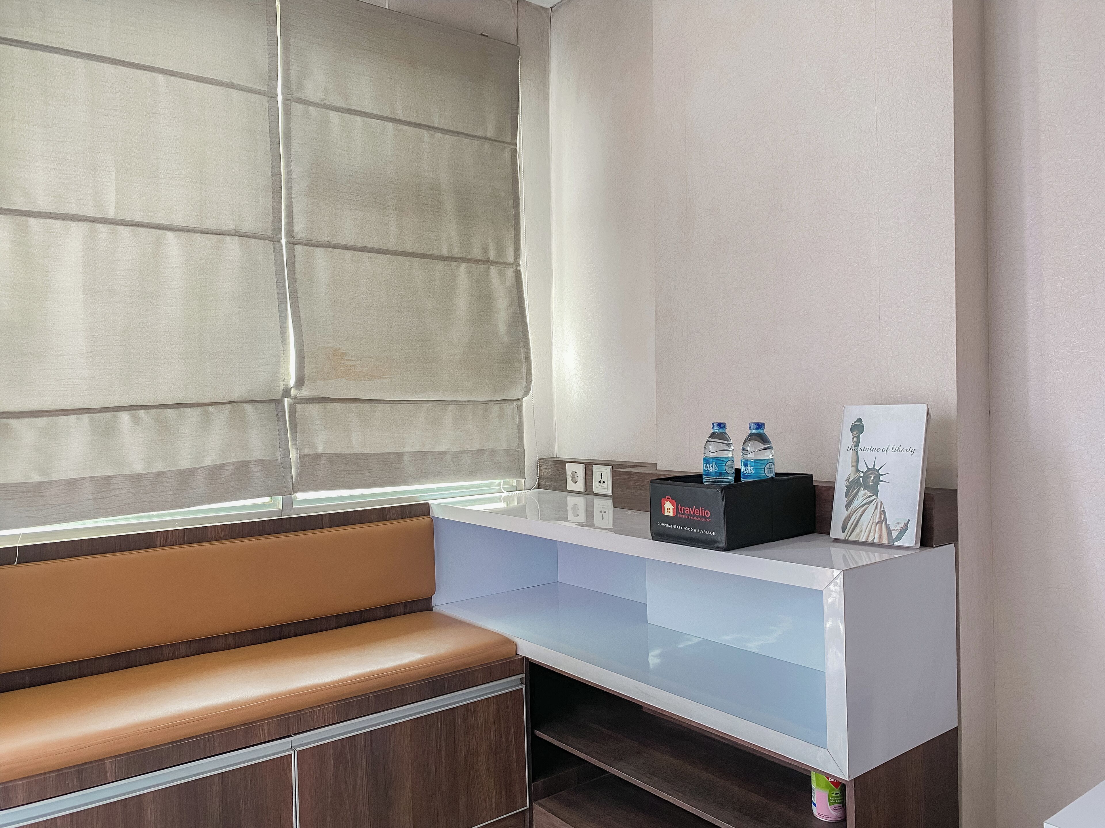 A hotel reception area with a cushioned bench, a glass-top desk, and a statue of the Statue of Liberty.