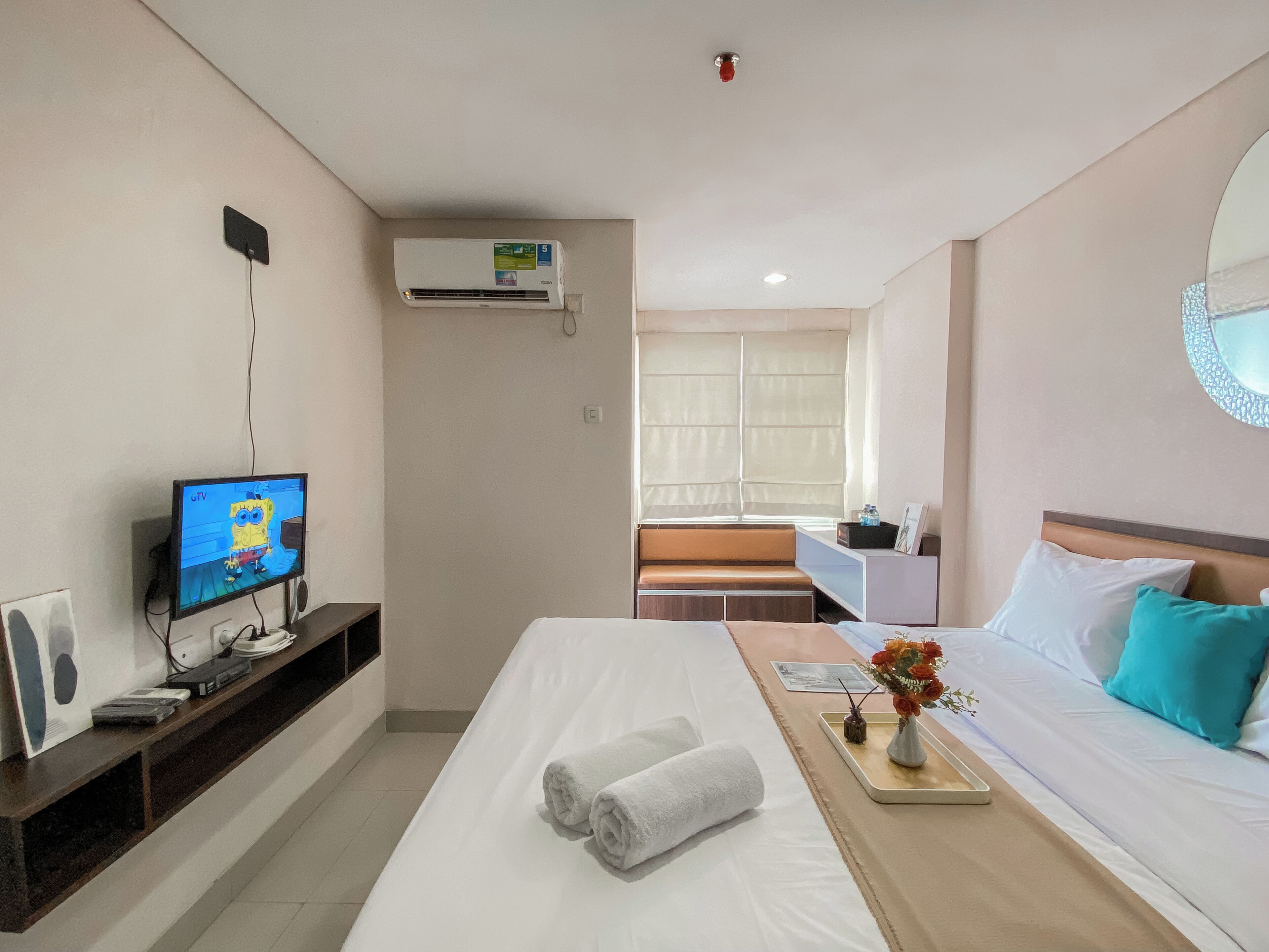 Una habitación de hotel con cama, televisión, escritorio y ventana.