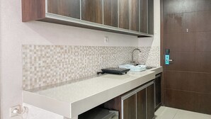 A kitchen with a white countertop, a tiled backsplash, and wooden cabinets.