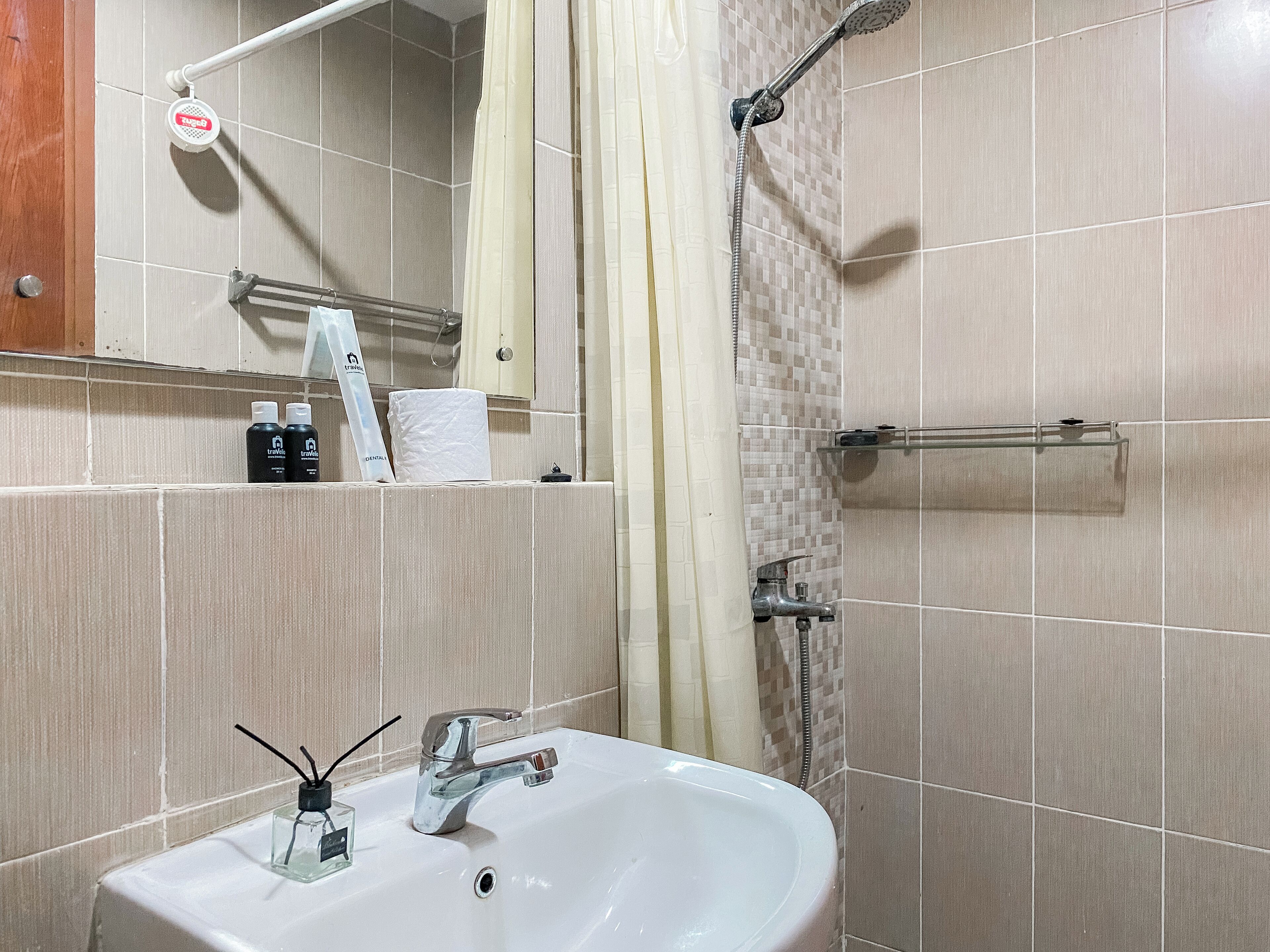 A bathroom with a sink, mirror, shower, and towel rack.