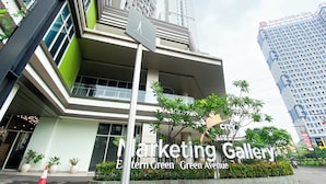 A modern building with a pedestrian crossing sign, surrounded by greenery and other high-rise buildings.
