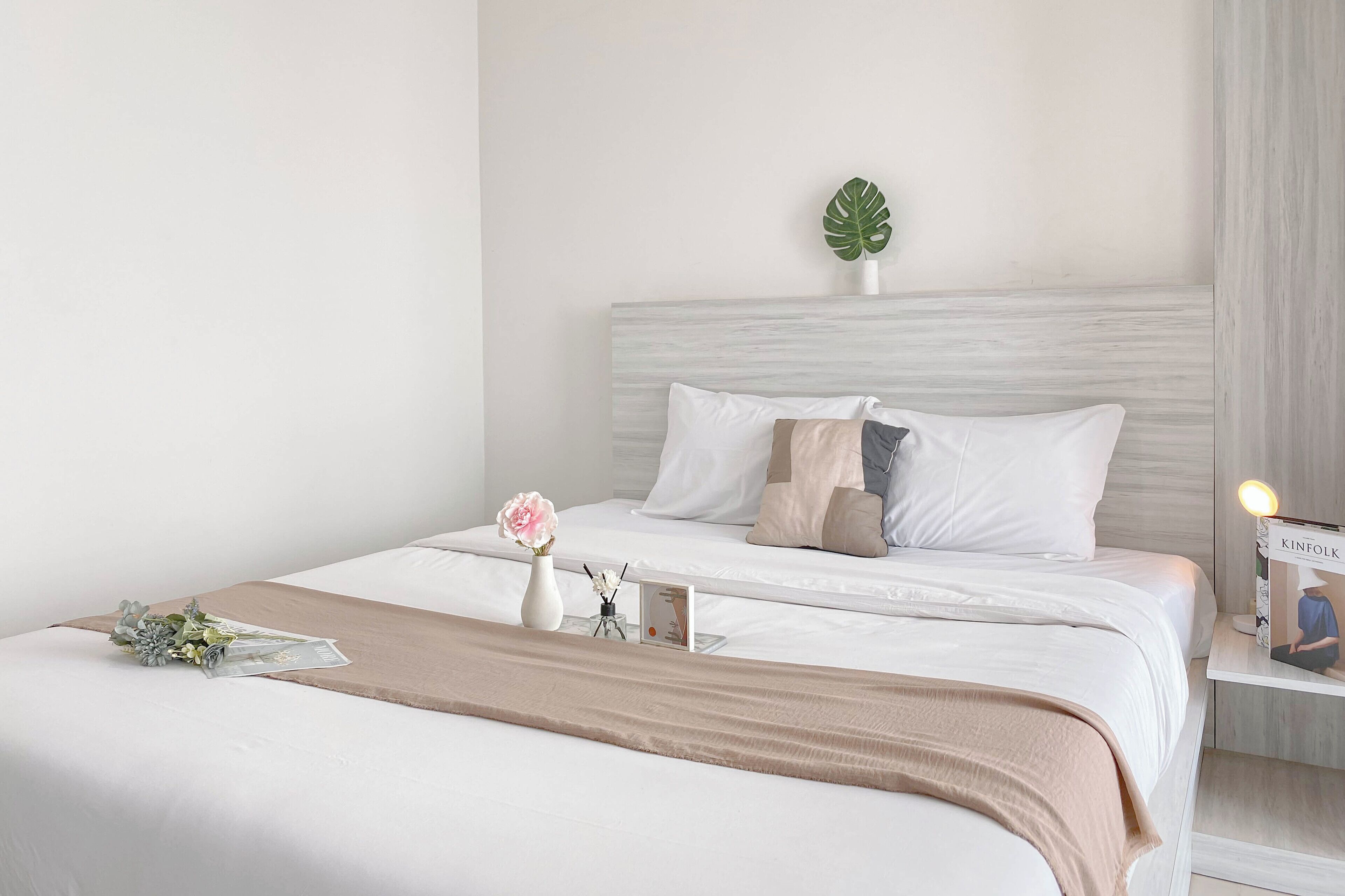 A neatly arranged bedroom with a bed, bedside table, and a potted plant.