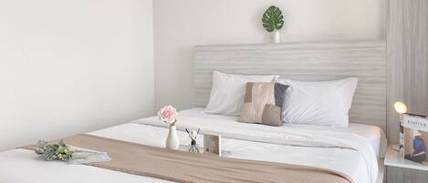 Un dormitorio ordenado con cama, mesita de noche y una planta en maceta.