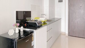 A modern kitchen with a black refrigerator, a sink with a yellow soap dispenser, and a white vase with flowers on the counter.