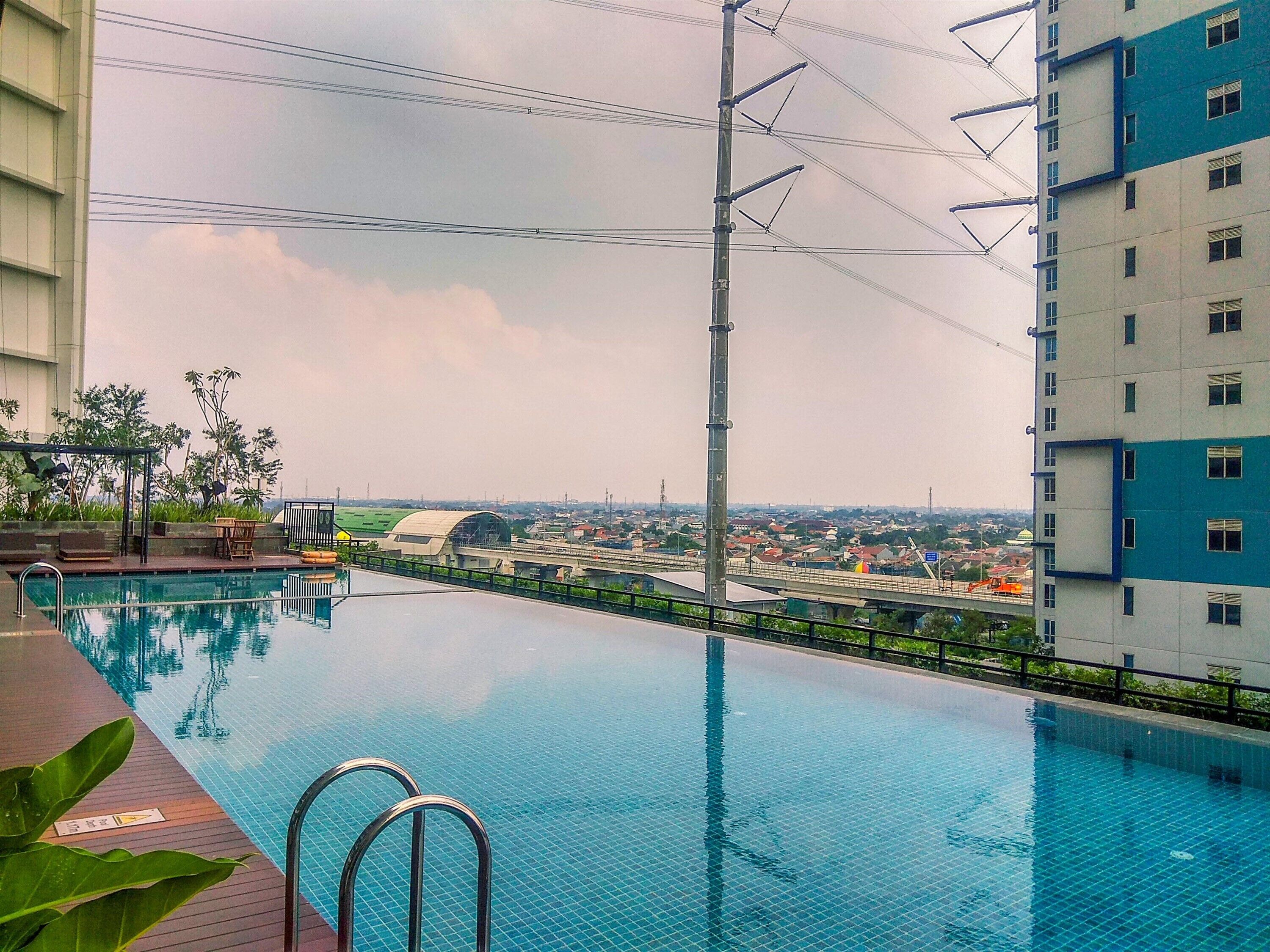 A swimming pool with a view of a cityscape, including a bridge and buildings.