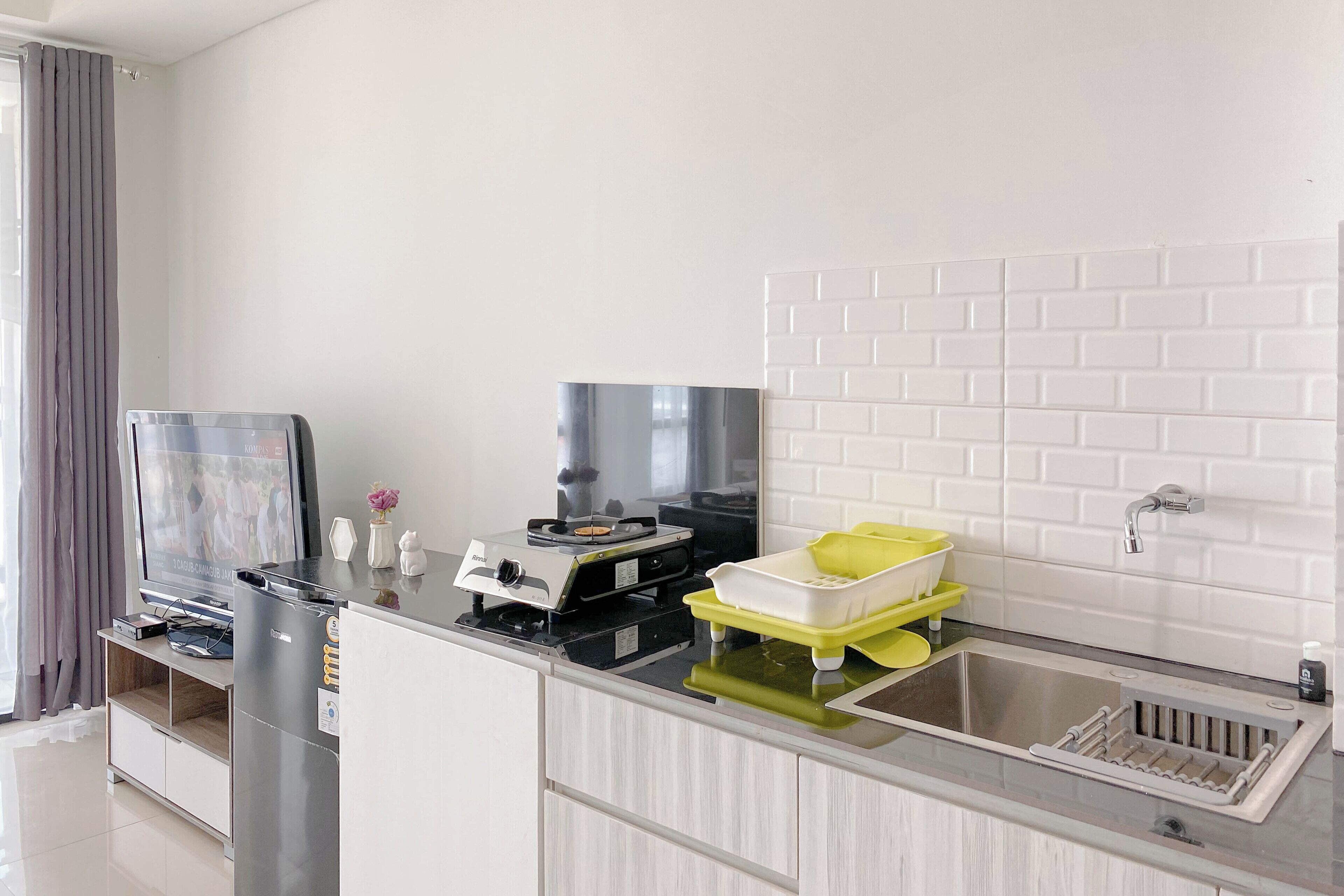 A modern kitchen with a built-in stove, a sink, and a flat-screen TV.