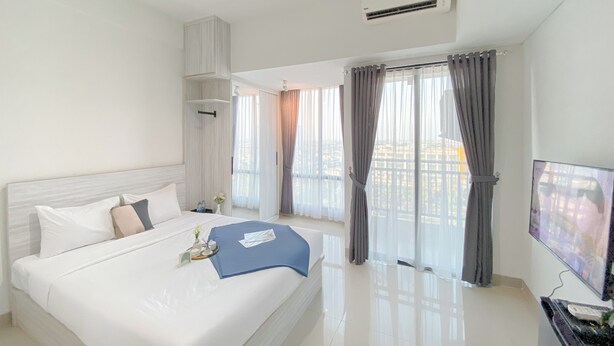 Una habitación de hotel moderna con una cama grande, televisión y un balcón con cortinas.
