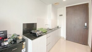 Una cocina moderna con encimera negra, armarios blancos y puerta de madera.