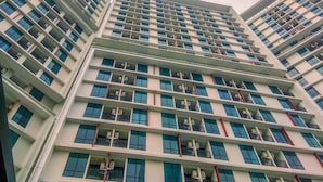 Un edificio de varios pisos con un diseño arquitectónico moderno, que cuenta con balcones en cada planta.