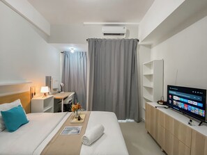 Habitación de hotel con dos camas, un escritorio con lámpara, televisión y aire acondicionado.