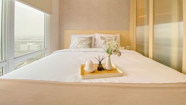 Une chambre d’hôtel avec un grand lit, une tête de lit en bois et une vue sur le paysage urbain, visible à travers une grande fenêtre.