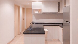 A modern kitchen with a black countertop, stainless steel sink, and white cabinetry.