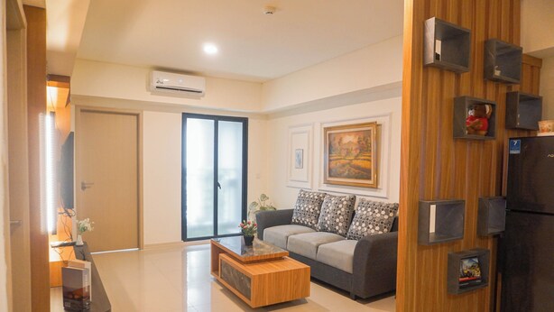 A modern living room with a sofa, coffee table, and built-in shelving. - Spacious 3Br Apartment At Meikarta (Cikarang)