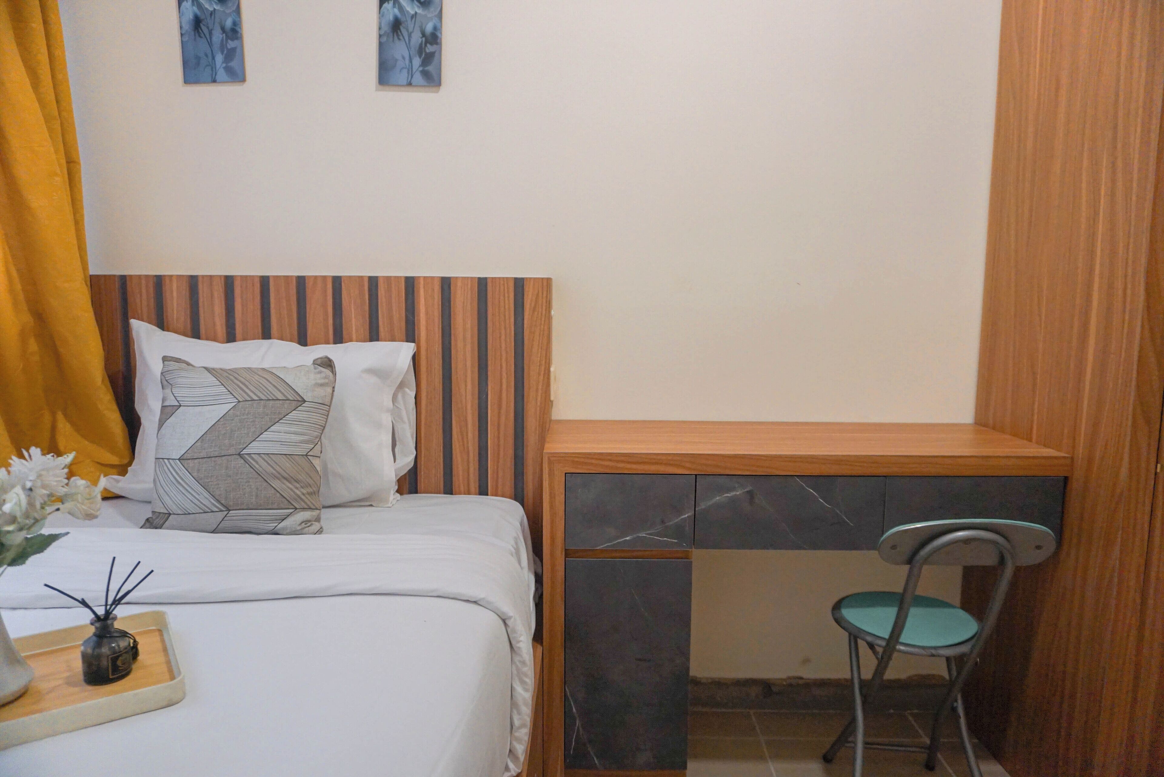 Una camera da letto con un letto, una scrivania, una sedia e un tavolino con un vaso.