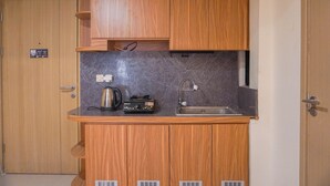 A compact kitchen with wooden cabinets, a built-in microwave, and a sink. - Spacious 3Br Apartment At Meikarta (Cikarang)