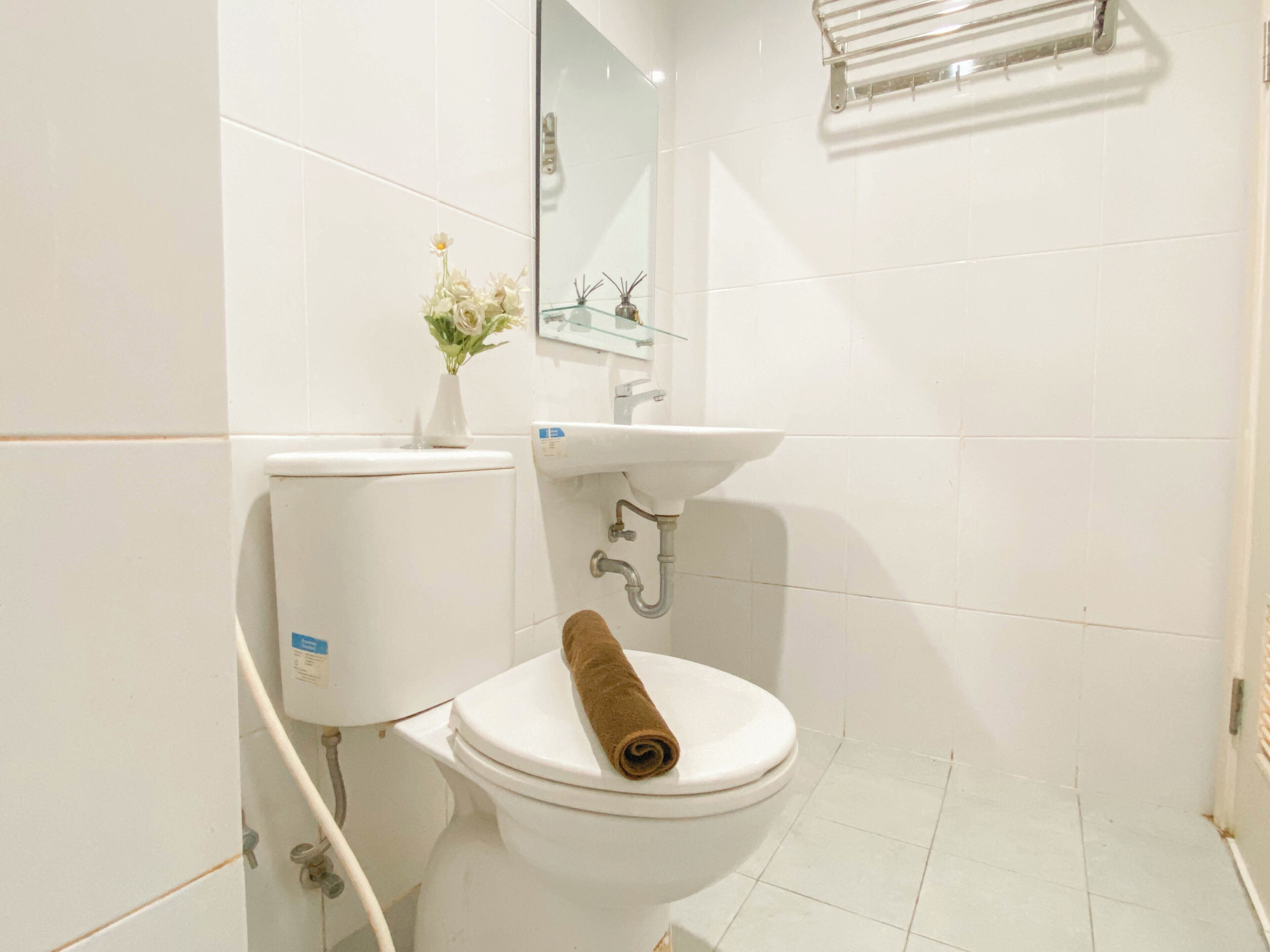Un inodoro blanco con una toalla, un lavabo y un espejo sobre él.