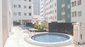 Un immeuble résidentiel doté d’une piscine, d’un espace extérieur aménagé et d’une zone couverte avec des plantes.