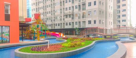 Un edificio moderno con parque acuático, toboganes y un puente.
