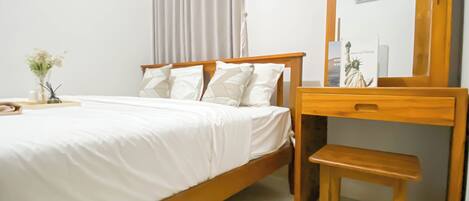 Un dormitorio con una cama de madera, una mesita de noche con lámpara, un espejo y una ventana con cortinas.