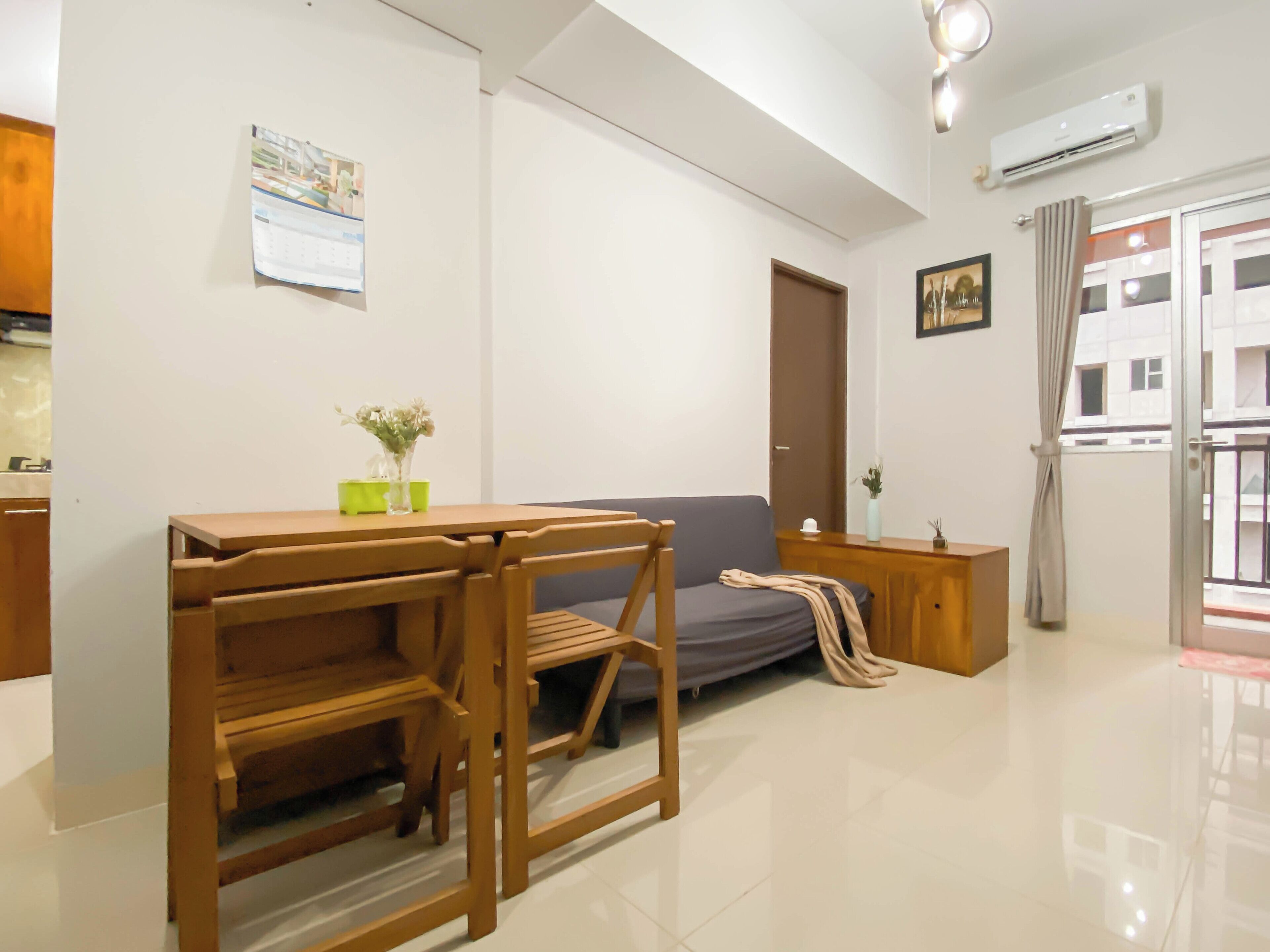 A modern living room with a wooden desk, grey sofa, and a small side table with a vase.