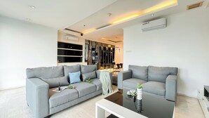 A modern living room with two grey sofas, a coffee table, and a decorative vase with flowers. - Spacious Luxury 2Br Apartment With Extra Room At Fx Residence (Jakarta)