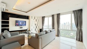 A modern living room with a large flat-screen TV, a sofa, and a coffee table. - Spacious Luxury 2Br Apartment With Extra Room At Fx Residence (Jakarta)