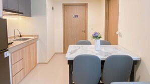 A compact kitchen with a sink, cabinets, and a dining table with chairs. - Warm 2Br Apartment At Meikarta (Cikarang)