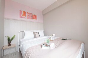 A bedroom with a bed, a bedside table, a plant, and wall art. - Soft Toned And Comfy 2Br Near Mall At Bassura City Apartment (Jakarta)