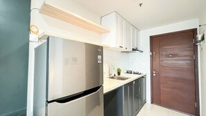 A compact kitchen with a built-in refrigerator, a sink, and cabinets.