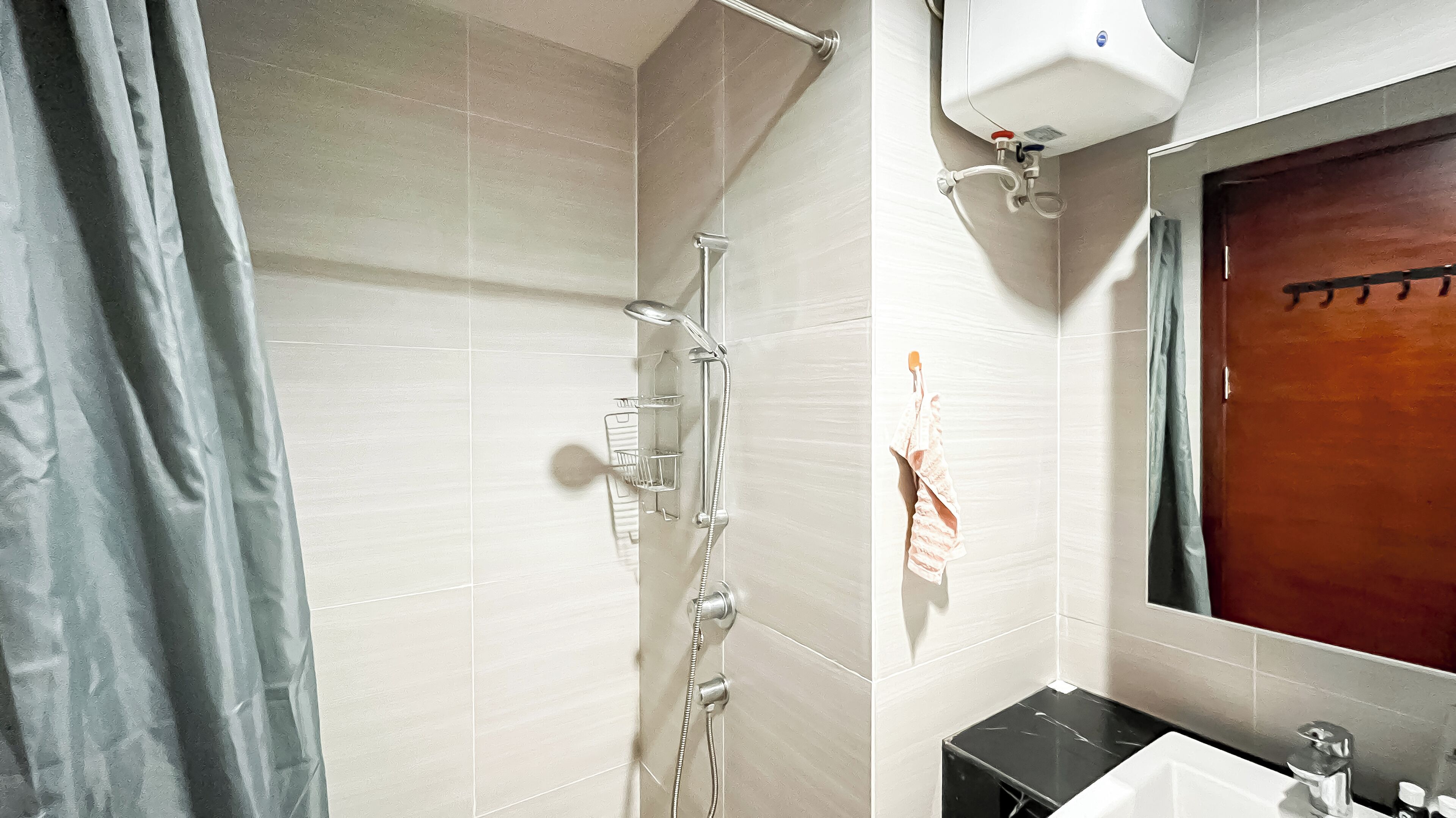 A bathroom with a shower, a towel rack, a sink, and a mirror.