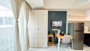 A modern kitchen with a built-in refrigerator, a wooden dining table, and a TV mounted on the wall.