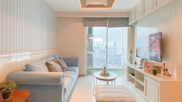 A modern living room with a sofa, a small table, and a TV on a stand. - Cozy Living 2Br Apartment Casa Grande Residence (Jakarta)