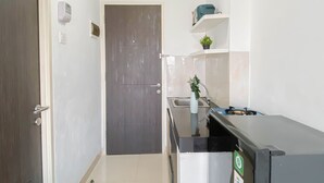 A compact kitchen with a refrigerator, a sink, and a small countertop. - Basic Studio Apartment Near Cisauk Station At Serpong Garden (Cisauk)