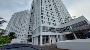 A modern high-rise building with a glass facade and multiple balconies. - Basic Studio Apartment Near Cisauk Station At Serpong Garden (Cisauk)